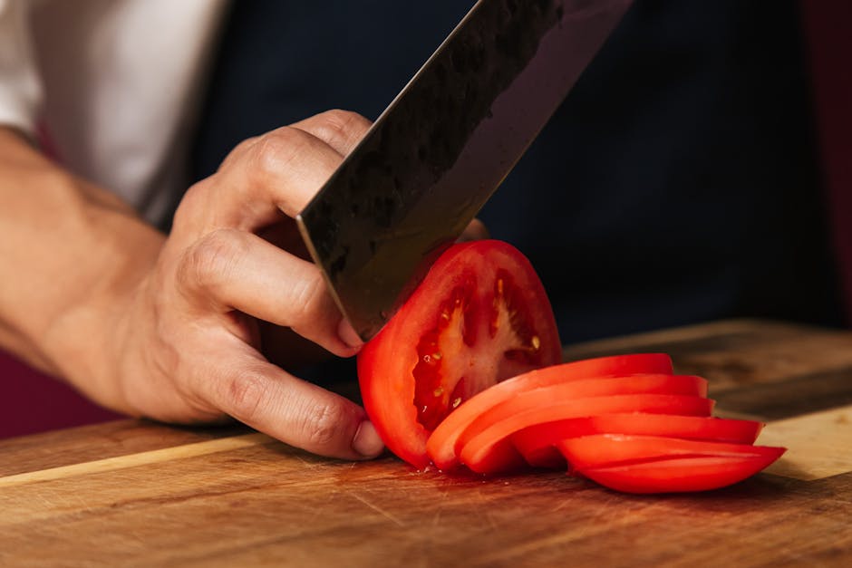 Sharp knife cutting fresh vegetables on wooden cutting board for food preparation
